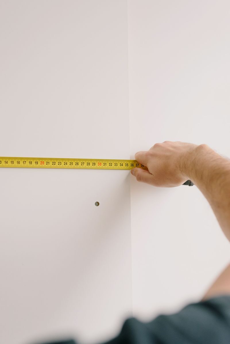 Crop unrecognizable male holding measuring tape while preparing for renovation works in room